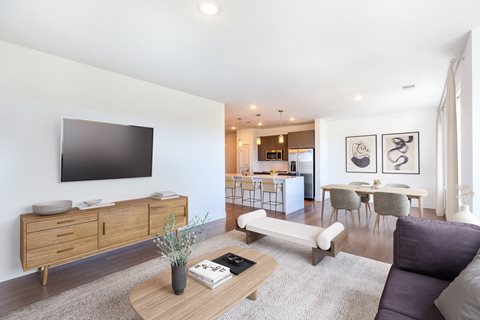 a living room with a large tv on the wall and a dining table and chairs in the
